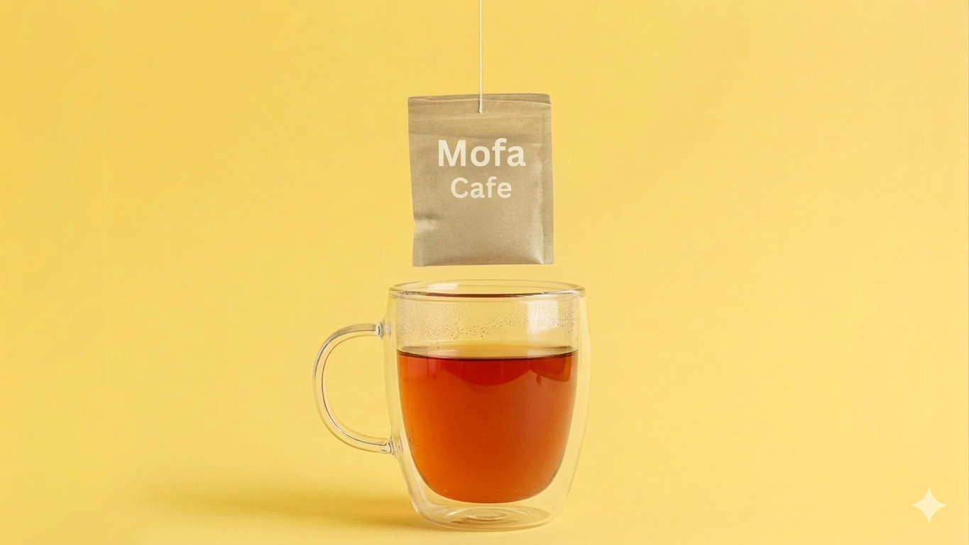 Tea bag labeled 'Mofa Cafe' hanging over a glass of tea on a yellow background